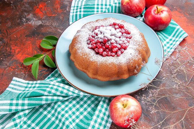 Vista ravvicinata laterale una torta una torta con mele di ribes rosso con foglie sulla tovaglia bianco-blu