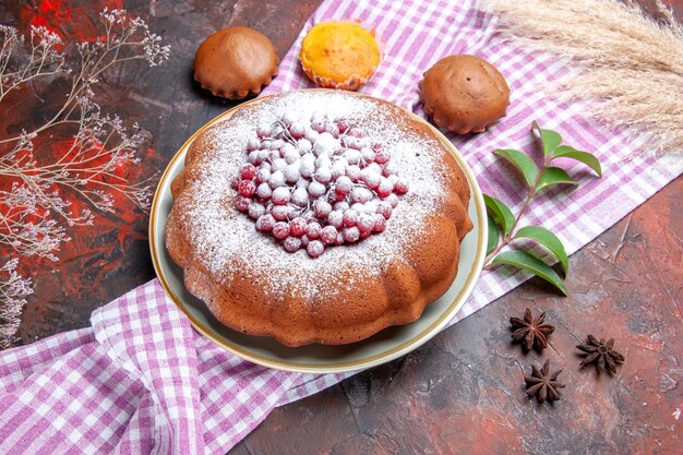 Vista ravvicinata laterale una torta una torta cupcakes lascia sulla tovaglia a quadretti anice stellato