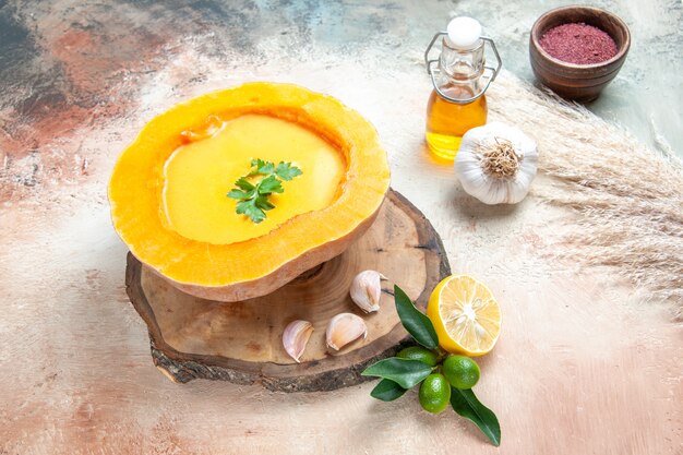 Vista ravvicinata laterale zuppa di zucca minestra con erbe aromatiche, aglio, limone, bottiglia di olio di spezie