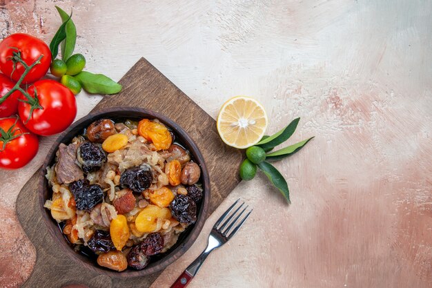 Vista ravvicinata superiore pilaf pilaf con frutta secca sulla forcella di bordo pomodori limone