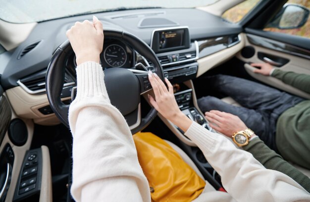 Vista ritagliata delle mani delle donne che guidano un'auto d'élite