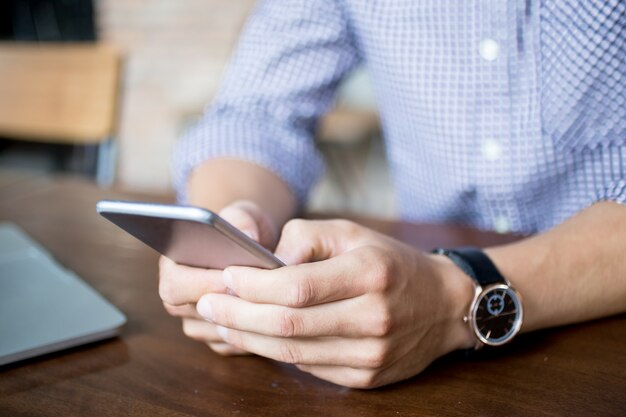 Vista ritagliata di uomo che tenta su smartphone