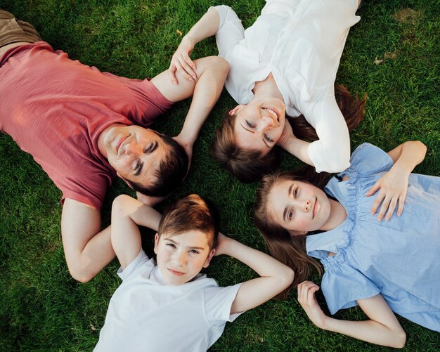 Vista sopraelevata della famiglia che si trova sull&#39;erba e che esamina macchina fotografica