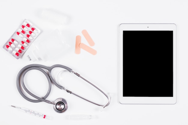 Vista sopraelevata delle attrezzature mediche con la compressa digitale sul contesto bianco