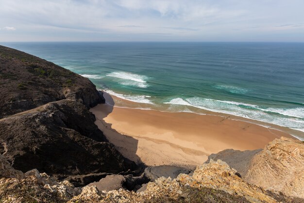 Vista su una spiaggia circondata dal mare e dalle rocce sotto un cielo blu in Portogallo, Algarve