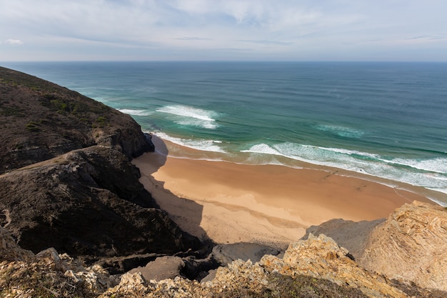 Vista su una spiaggia circondata dal mare e dalle rocce sotto un cielo blu in Portogallo, Algarve