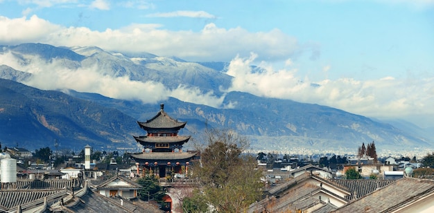 Vista sul tetto della città vecchia di Dali con il nuvoloso Monte Cangshan. Yunnan, Cina.