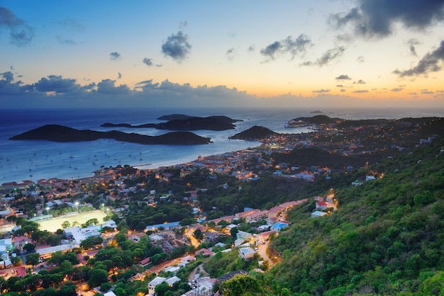 Vista sulle montagne al tramonto di San Tommaso delle Isole Vergini con nuvole colorate, edifici e costa della spiaggia.