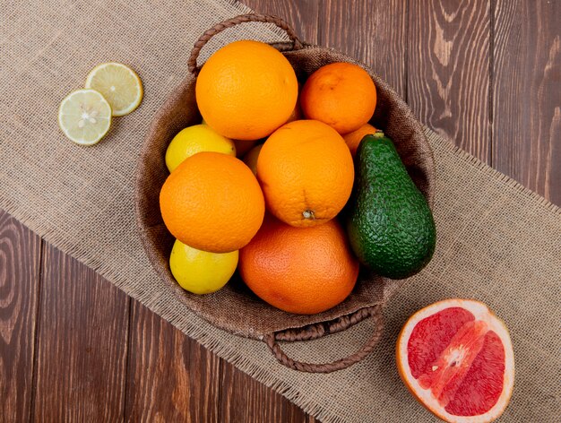 Vista superiore degli agrumi come merce nel carrello arancio del limone dell'avocado con il pompelmo su tela di sacco e fondo di legno