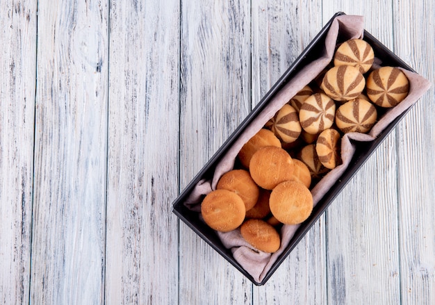 Vista superiore dei biscotti a strisce deliziosi dolci in un vassoio nero su fondo di legno con lo spazio della copia