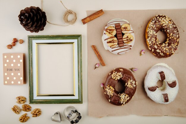 Vista superiore dei biscotti con cannella e noci e pinecone e struttura su bianco con lo spazio della copia