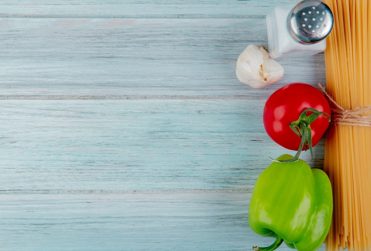 Foto gratuito vista superiore dei maccheroni dei vermicelli con l'aglio e il sale del pepe del pomodoro su superficie di legno con lo spazio della copia