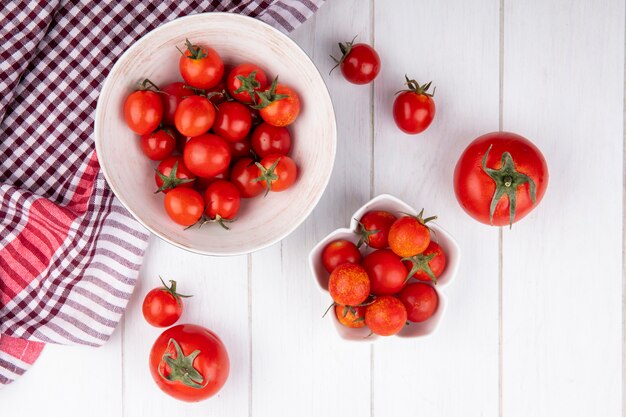 Vista superiore dei pomodori in ciotole sul panno del plaid e su superficie di legno