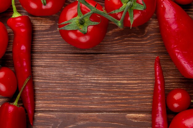 Vista superiore dei pomodori maturi degli ortaggi freschi con i peperoncini rossi su legno rustico con lo spazio della copia