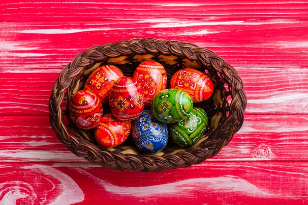 Vista superiore del cesto con uova di Pasqua sulla superficie in legno