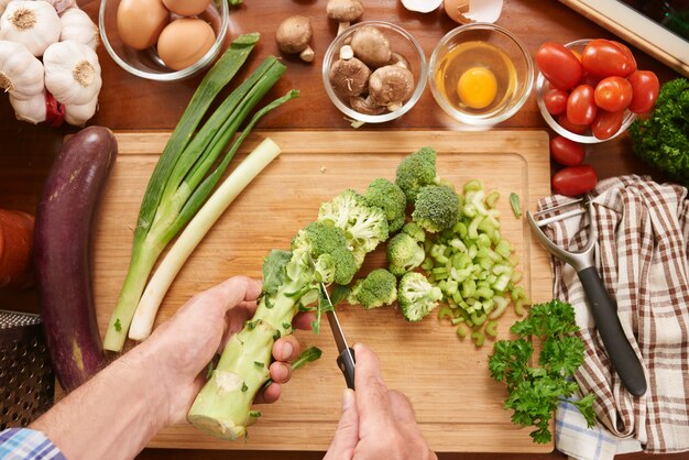 Vista superiore del cuoco irriconoscibile che prepara le verdure verdi