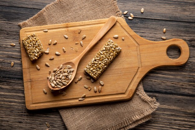 Vista superiore del kozinaki dolce dei semi di girasole e un cucchiaio di legno sul bordo di legno