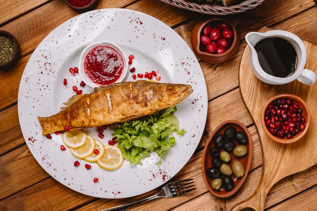 Vista superiore del piatto di pesce fritto guarnito con lattuga al limone e salsa rossa