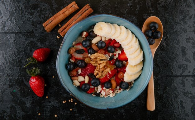 Vista superiore del porridge di farina d'avena con cucchiaio di legno e bastoncini di cannella