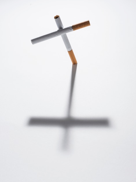 Vista superiore del segno trasversale fatto dalla sigaretta con ombra su isolato su fondo bianco