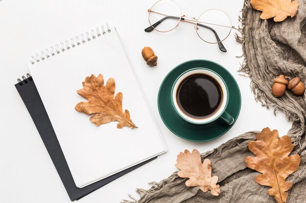 Vista superiore del taccuino con caffè e foglie di autunno