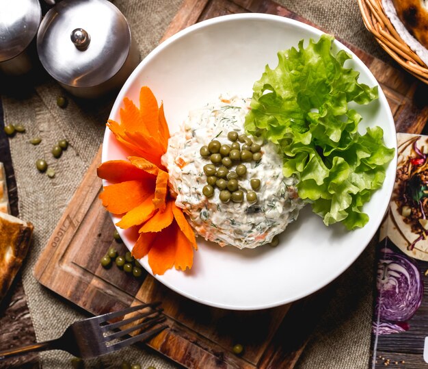 Vista superiore dell'insalata dell'oliva guarnita con i fiori e la lattuga della carota