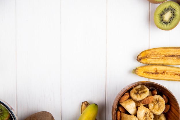 Vista superiore della banana e dei kiwi freschi su legno bianco con lo spazio della copia