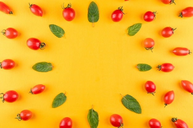 Vista superiore della menta e dei pomodori ciliegia su superficie gialla con lo spazio della copia