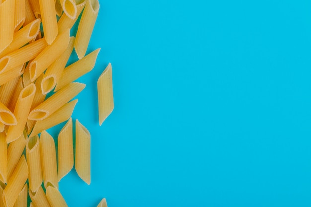 Vista superiore della pasta del penne dalla parte di sinistra e dalla superficie del blu con lo spazio della copia