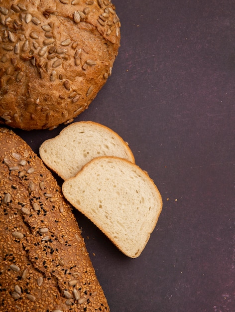 Vista superiore delle fette del pane bianco con la pannocchia e le baguette dalla parte di sinistra e dal fondo marrone rossiccio con lo spazio della copia