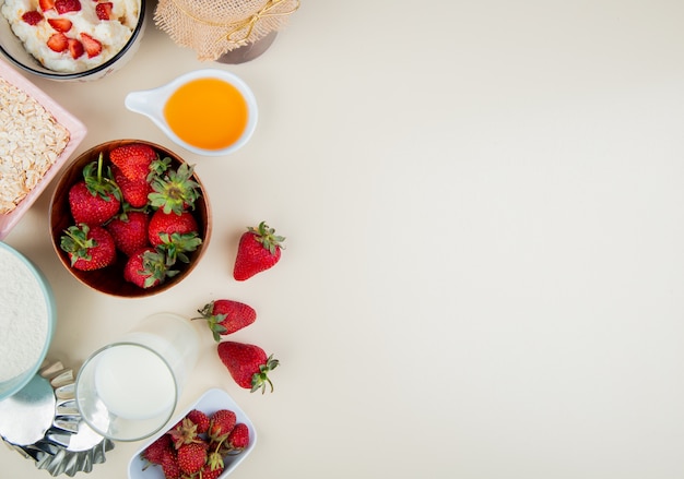 Vista superiore delle fragole in ciotola con l'avena del latte di ricotta sul lato sinistro e bianco con lo spazio della copia