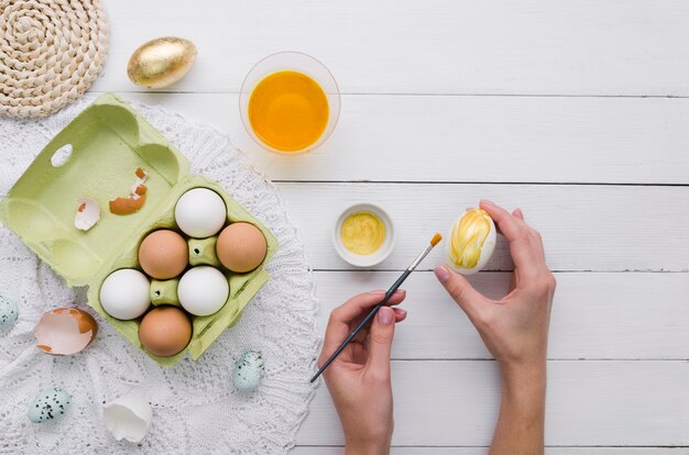 Vista superiore delle mani che tingono uovo per pasqua