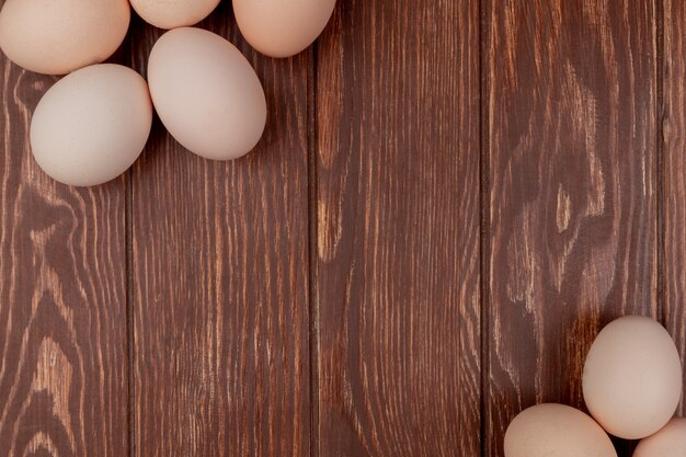 Vista superiore delle uova color crema del pollo isolate su un fondo di legno con lo spazio della copia