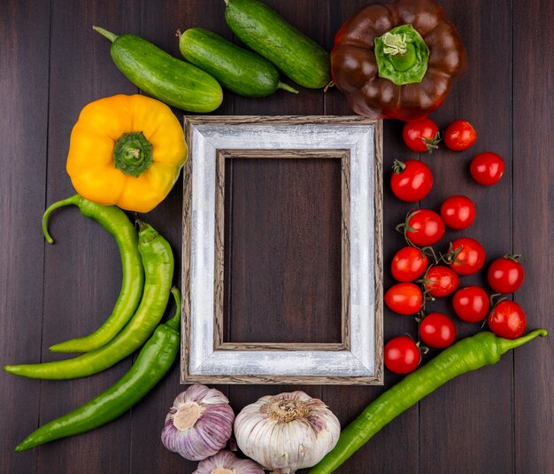 Vista superiore delle verdure come aglio del cetriolo del pomodoro del pepe intorno alla struttura su superficie di legno