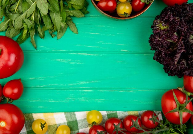 Vista superiore delle verdure come basilico verde del pomodoro delle foglie di menta su superficie verde con lo spazio della copia