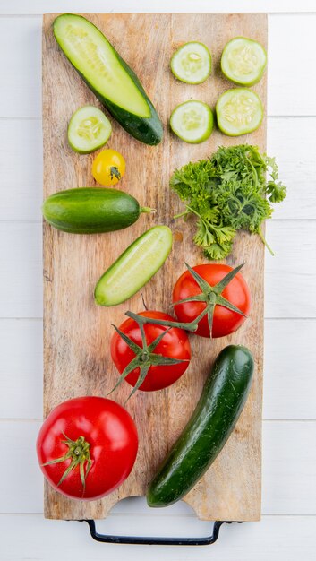 Vista superiore delle verdure come coriandolo del pomodoro del cetriolo sul tagliere su legno