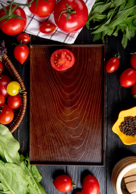 Vista superiore delle verdure come spinaci delle foglie di menta di verde di pomodoro e pomodoro tagliato in vassoio su superficie di legno