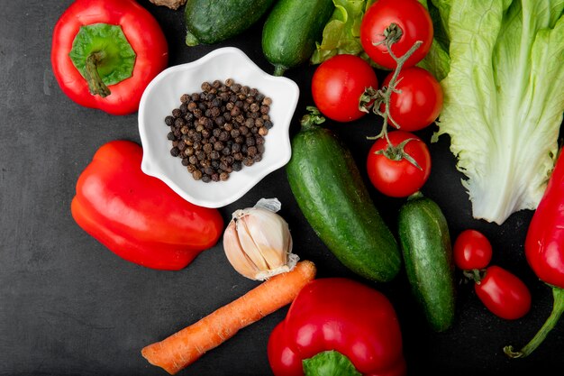 Vista superiore dello spazio del pepe con la carota dell'aglio del cetriolo del pepe e altre verdure su fondo nero