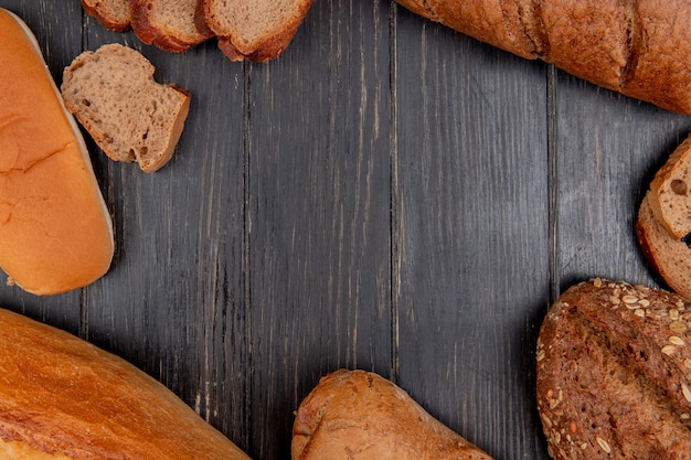 Vista superiore di diversi pani come sandwich di baguette nero di segale un su fondo di legno con lo spazio della copia