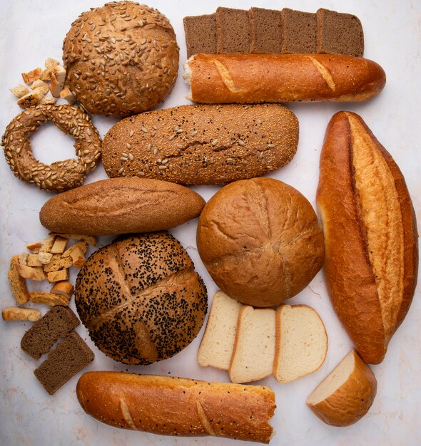 Vista superiore di diversi tipi di pane come baguette bagel bianco e segale su sfondo bianco