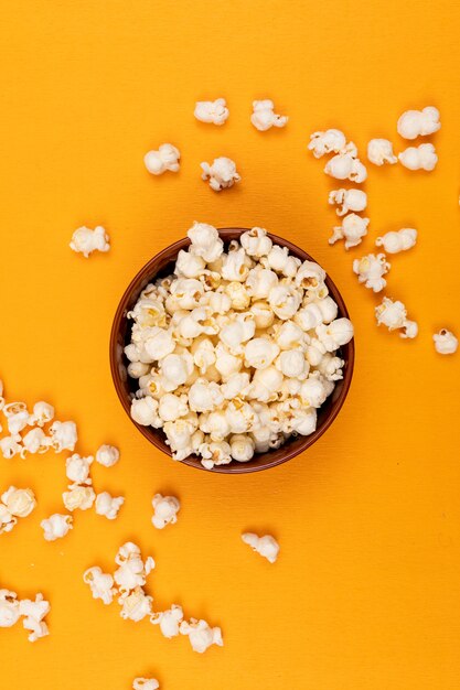 Vista superiore di popcorn in ciotola sul verticale giallo