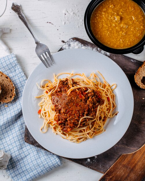 Vista superiore di spaghetti alla bolognese sul piatto bianco