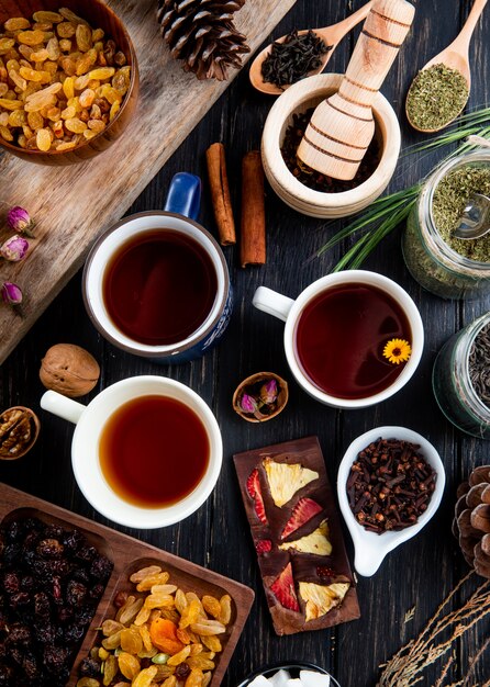 Vista superiore di tazze di tè e varie spezie ed erbe con noci miste e frutta secca su rustico