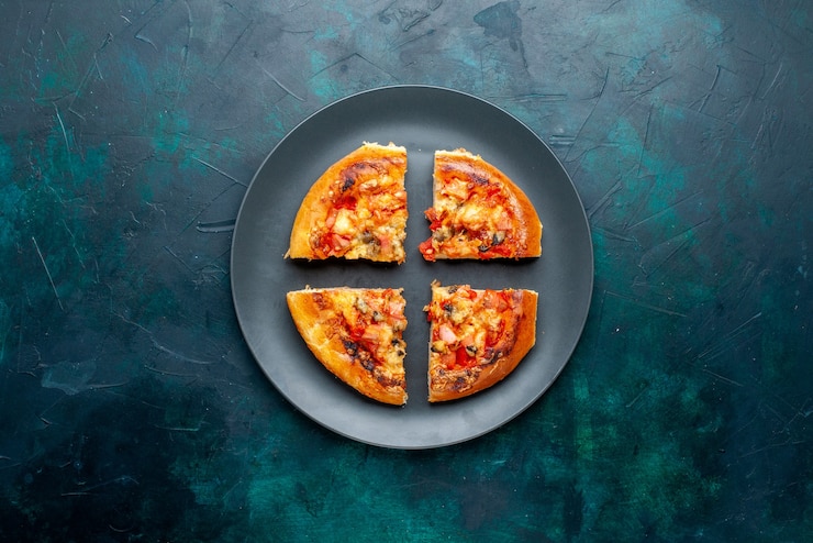 Foto gratuito vista superiore di una piccola pizza al formaggio tagliata all'interno di un piatto su una superficie blu scuro