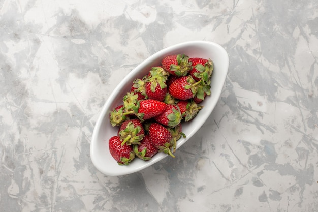 Vista superiore fragole rosse fresche bacche all'interno del piatto sulla superficie bianca bacca frutta pianta albero freschezza