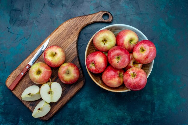 Vista superiore mele rosse fresche succose e pastose all'interno del piatto con coltello sulla scrivania blu scuro frutta fresca e matura vitamina mellow