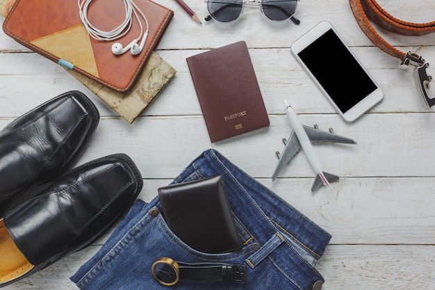 Vista superiore uomini accessori per viaggiare concept.White telefono cellulare e cuffie su background.airplane di legno, cappello, passaporto, orologio, occhiali da sole sul tavolo di legno.