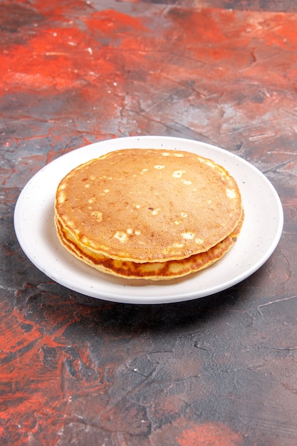 Vista verticale dei pancake americani classici del latticello sulla zolla bianca sul colore misto