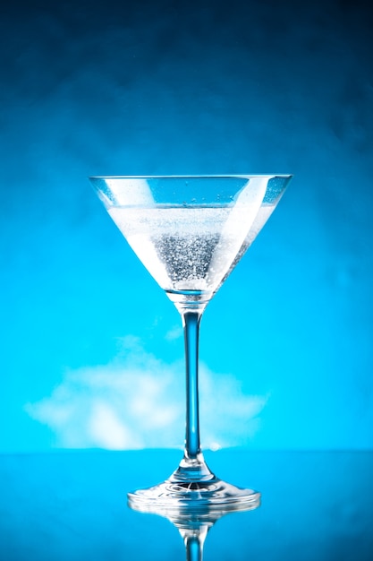 Vista verticale del calice di vetro per vino in piedi sul lato destro su sfondo blu
