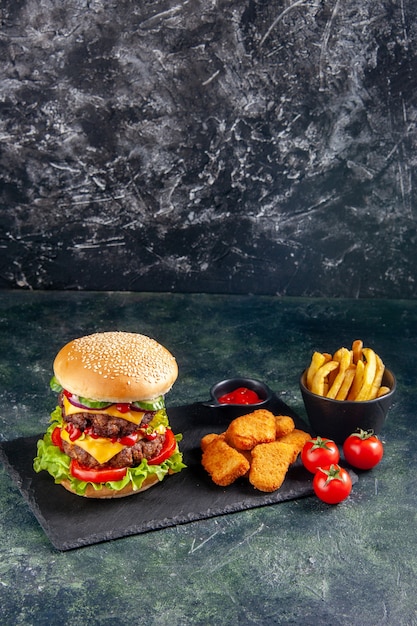 Vista verticale del delizioso panino e ketchup di pepite di pollo sui pomodori vassoio di colore scuro sulla superficie nera